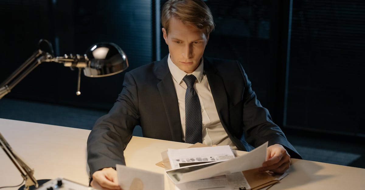 Focused investigator reviewing evidence in a dimly lit office setting.